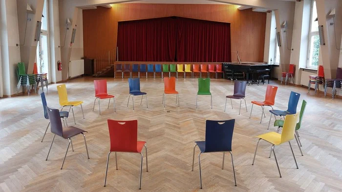 Stuhlkreis aus bunten Stühlen im großen Saal